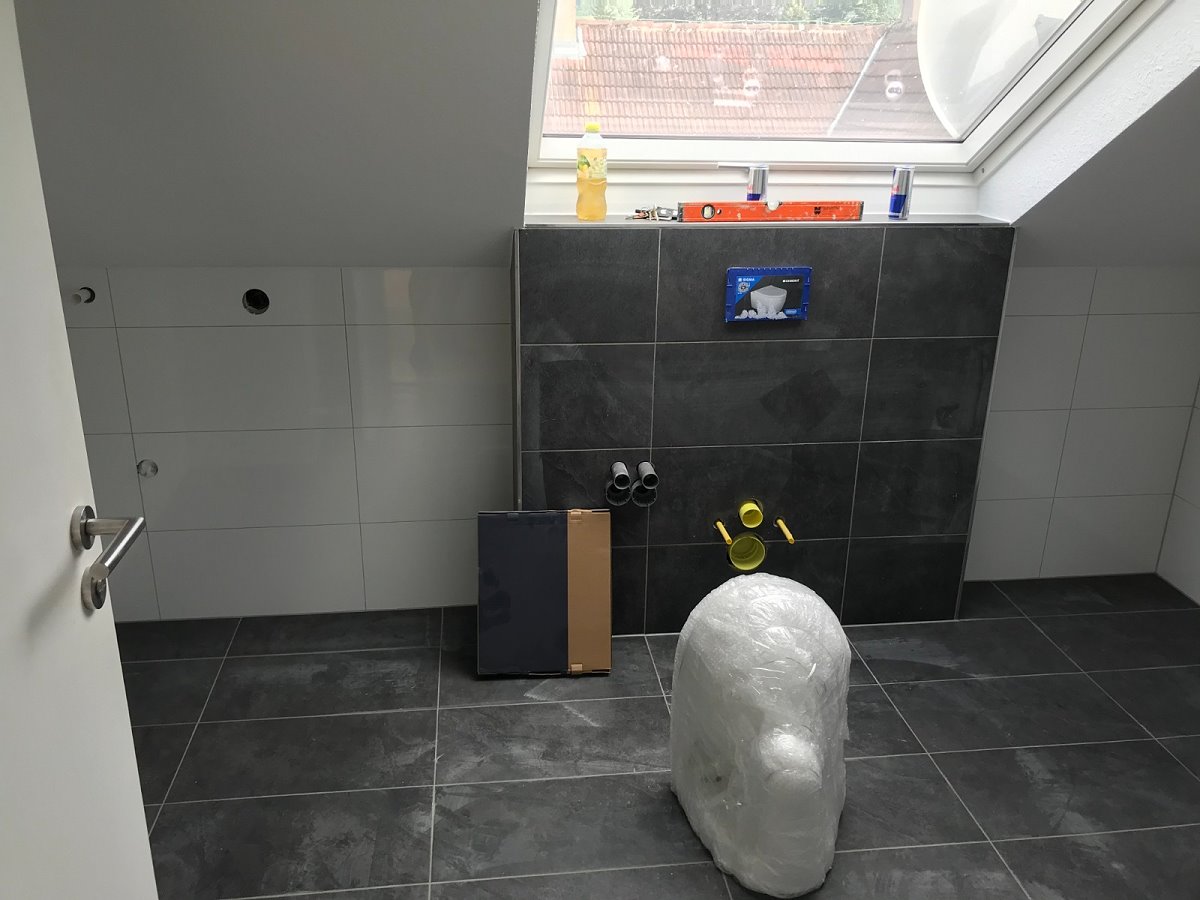 Ein Bad mit Schwarzen Fliesen unter einer Dachschräge